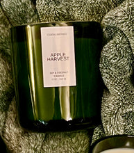 Load image into Gallery viewer, 12 green jar candle with wood wick and lid, apple harvest scent, on side on top of green fuzzy blanket 
