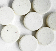 Load image into Gallery viewer, White speckled shower steamer pucks on a textured white surface
